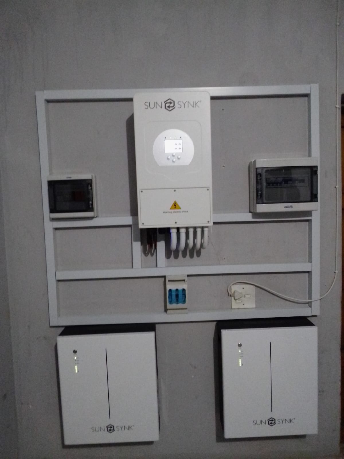 Wall-mounted Sunsynk inverter with two battery modules and distribution boards